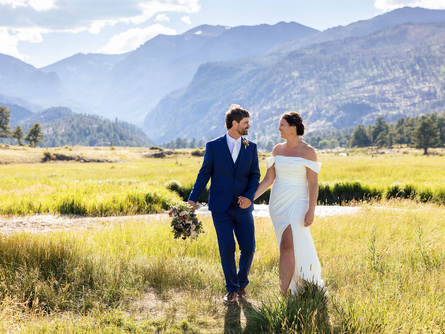 Anne & Josh walk through a scenic mountain field after their Rocky Mountain National Park Elopement.