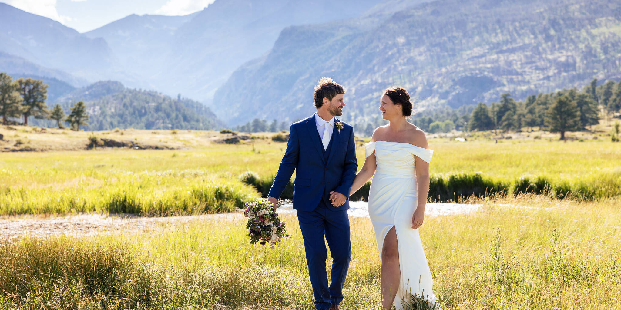 Anne & Josh walk through a scenic mountain field after their Rocky Mountain National Park Elopement.