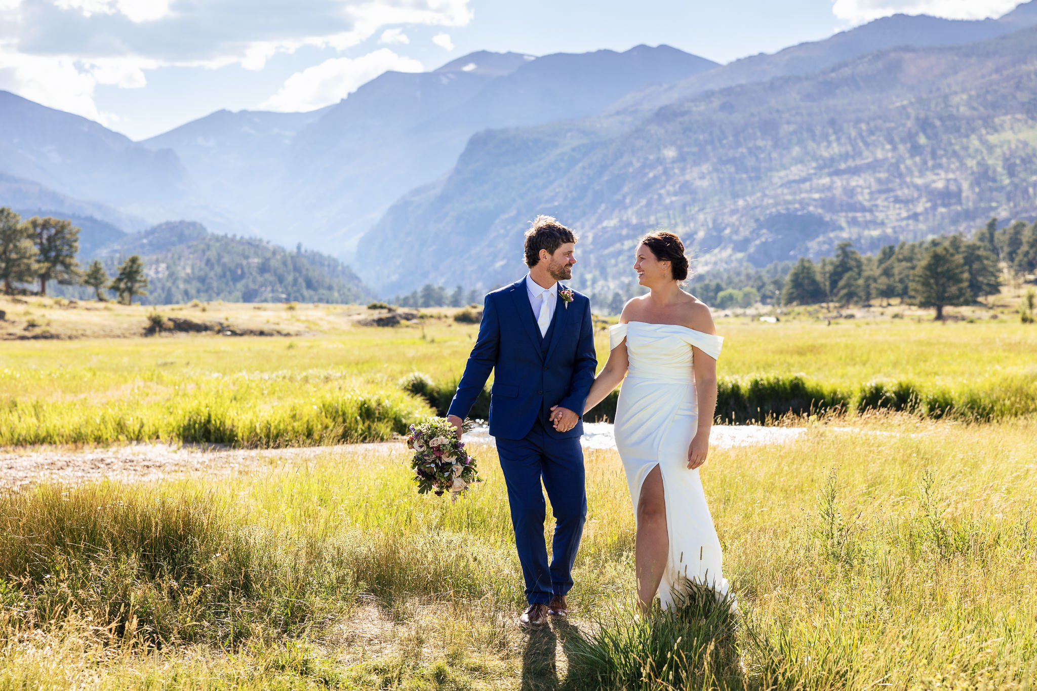 Anne & Josh walk through a scenic mountain field after their Rocky Mountain National Park Elopement.