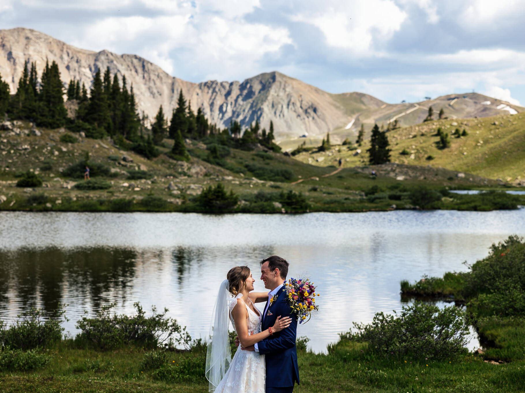 Jenni & Mike are hugging with the mountains and lake in the background after their Loveland Pass elopement.