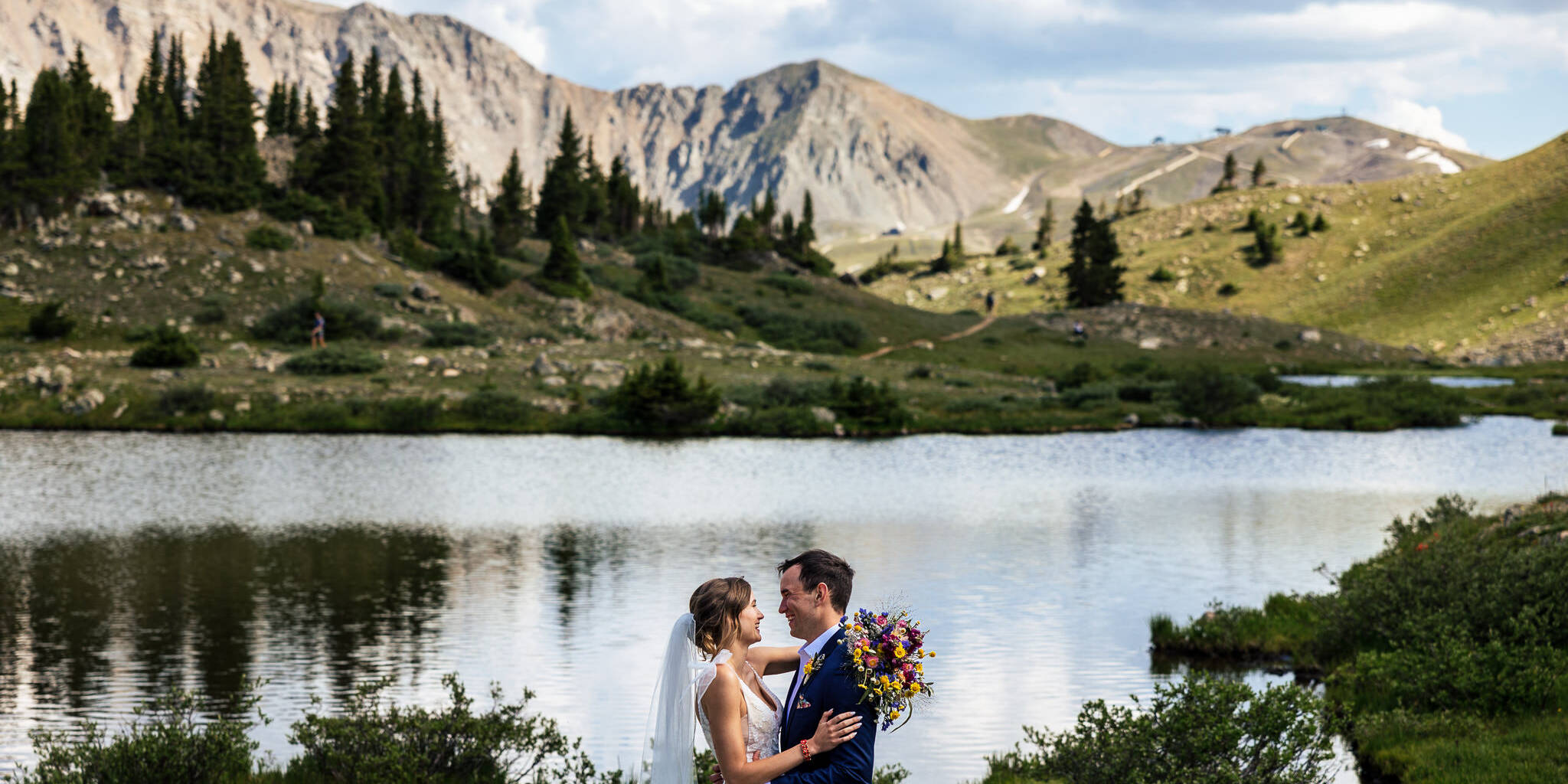 Jenni & Mike are hugging with the mountains and lake in the background after their Loveland Pass elopement.