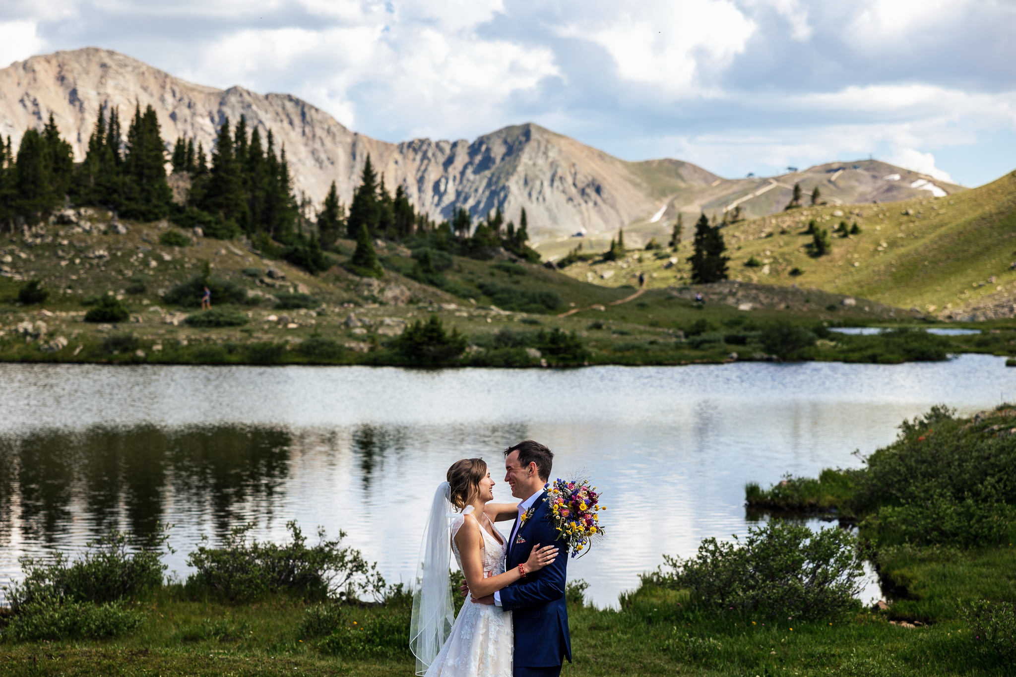 Jenni & Mike are hugging with the mountains and lake in the background after their Loveland Pass elopement.